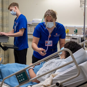 Students practice taking vital signs with a standardized patient in the practice lab. 