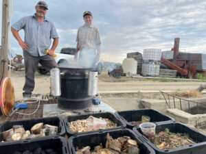 Deron Beck, a scientific aide at the UI Parma Research and Extension Center, left, and Mike Thornton, a U of I plant sciences professor in Parma, stand by the smoker they use to simulate wildfire smoke and its effects on potatoes, as well as trays filled with different types of wood to make the most accurate wildfire smoke simulation possible.