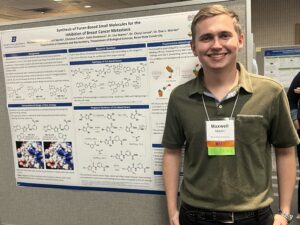 Photo of Maxwell Martin standing in front of his research poster