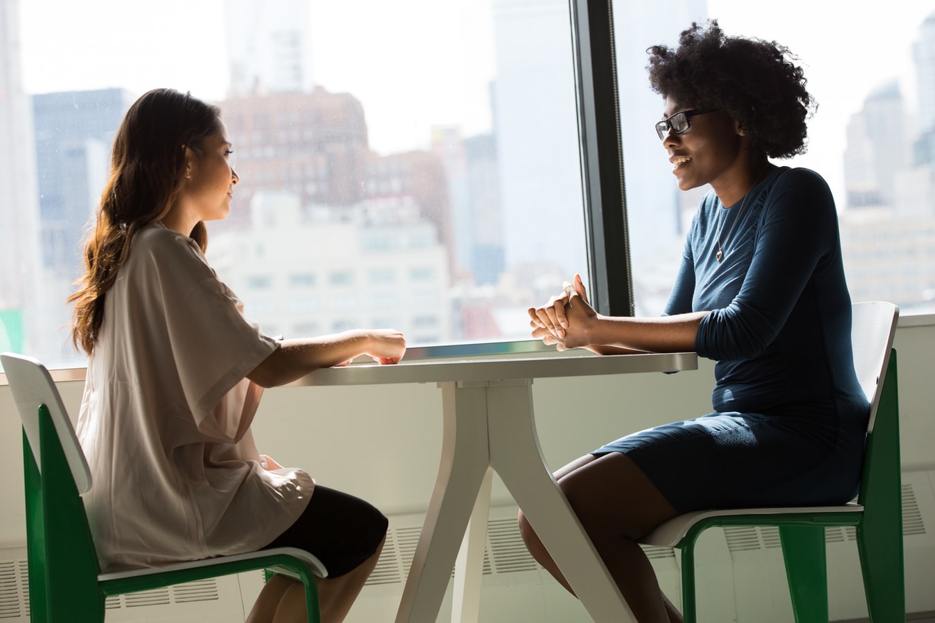 Two women talking at a table, practicing for an interview.