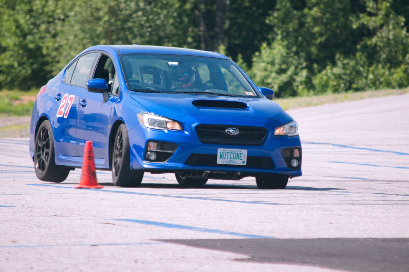 Justin Malinosky drives a blue Subaru around a cone in a parking lot.