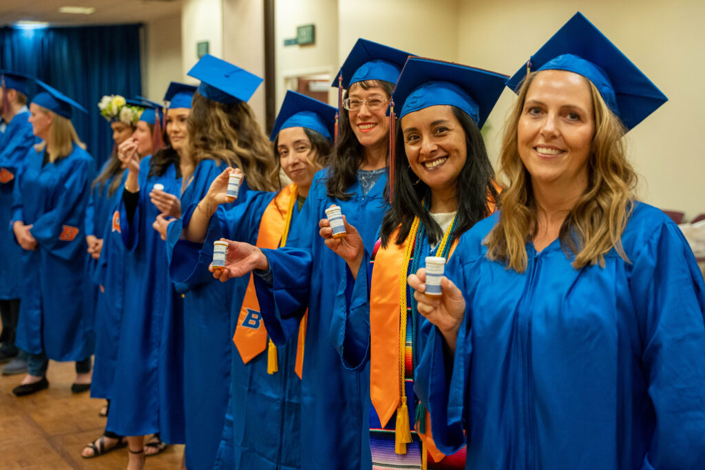 RN-BS graduates pose with fake pill bottles containing skittles