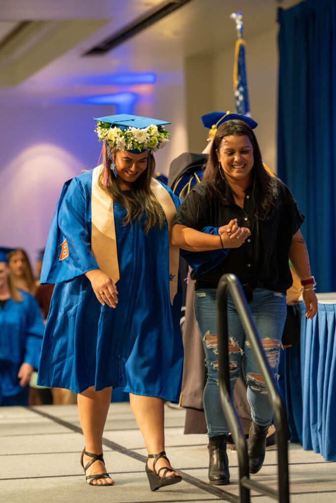 A pre-license graduate smiles and holds hands with her escort as they leave the stage