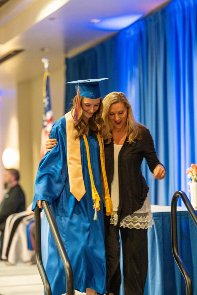 A pre-license graduate smiles and hugs her escort as they leave the stage