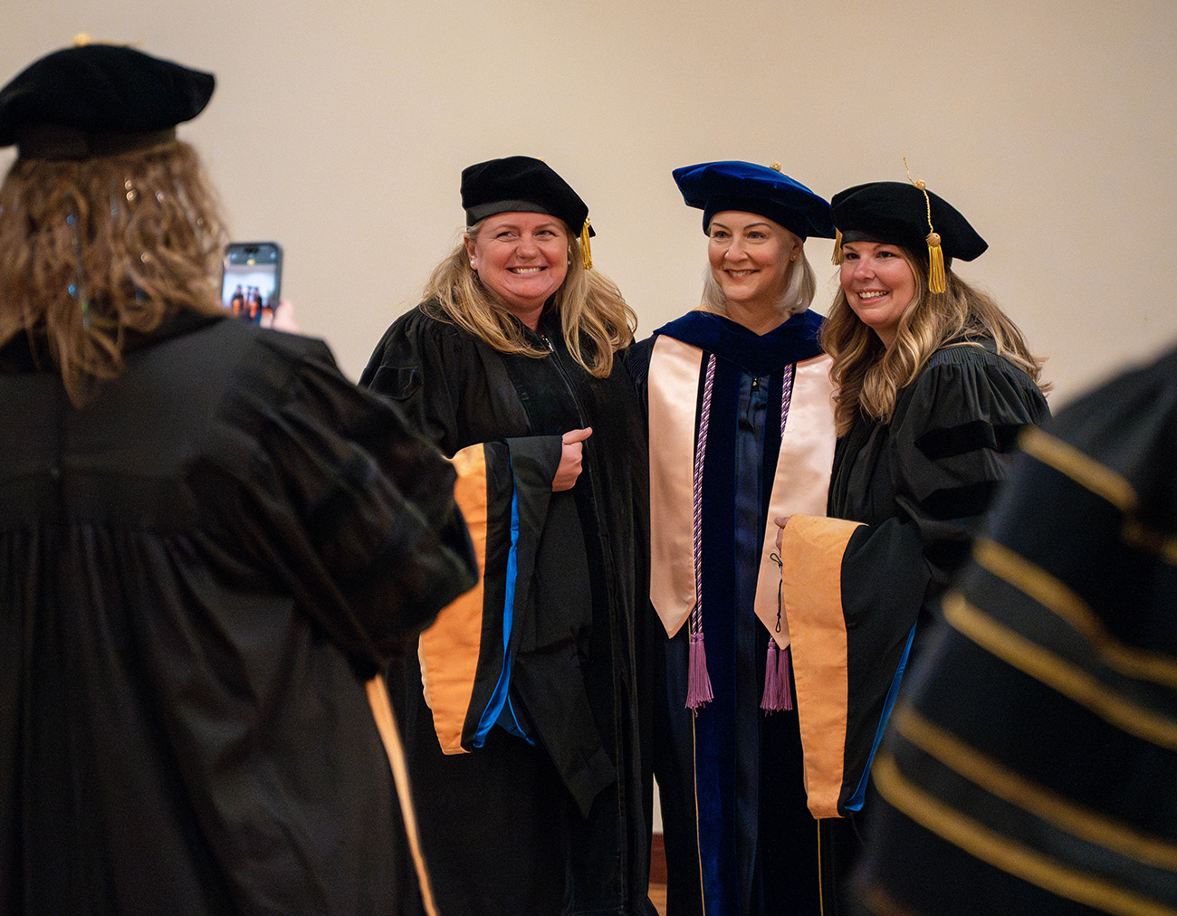 Lauren Kalember poses with a DNP student and professor for a photo in their regalia.