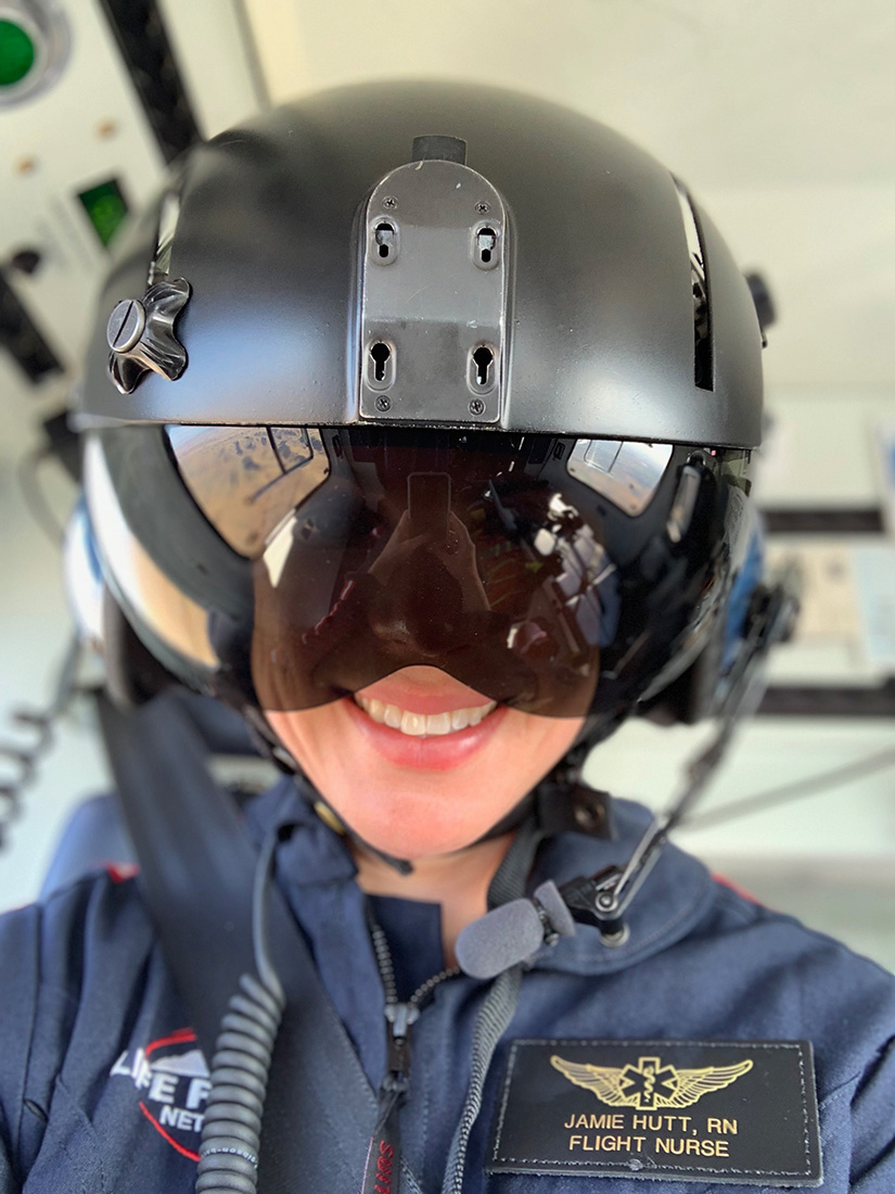 Selfie of Jamie Hutt in the helicopter wearing her helmet and flight suit.