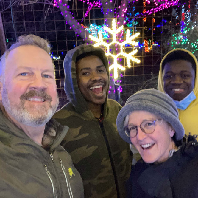 Craft and her husband stand with Patrick and his brother in front of holiday lights.