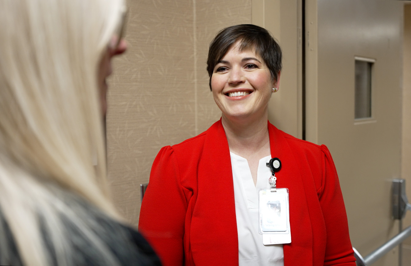 In a hallway, Lauren Smith smiles at a woman in the foreground.