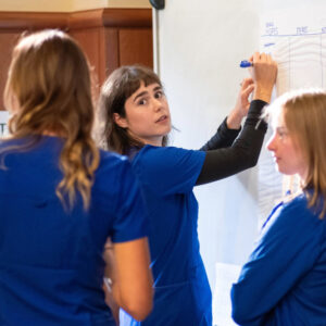 A Nursing Student writes on a whiteboard during a group activity.