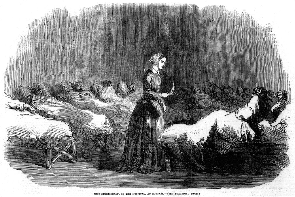 Black and white wood engraving of a nurse holding a lamp while standing between rows of hospital beds in the late 1800s. The caption reads: Miss Nightingale, In the hospital, at Scutari
