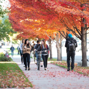 Students walking together on campus. one is walking with a bike as they chat