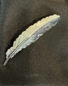 close up of sliver writing quill label pin