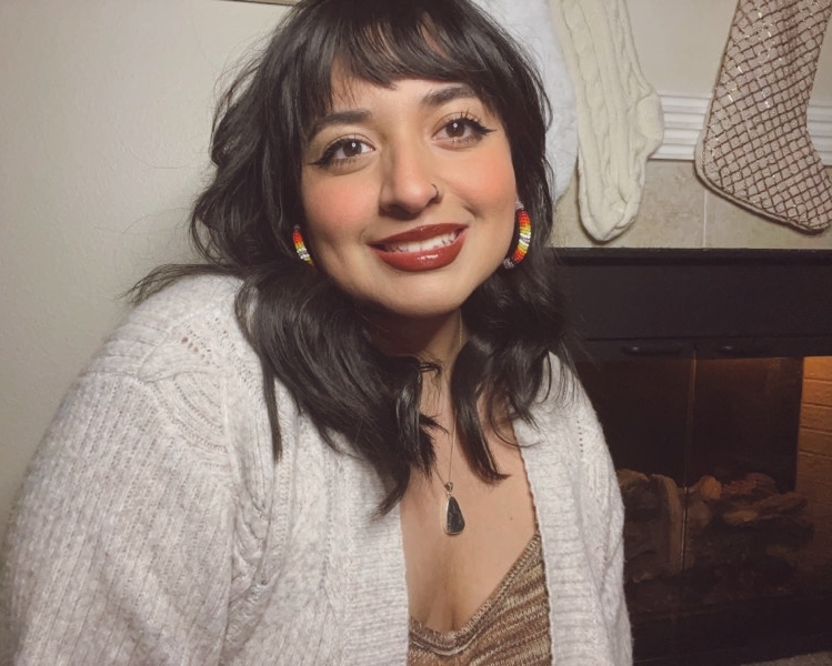 Brandee Robles is pictured wearing a white cardigan sweater. 