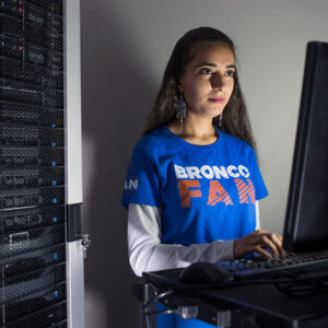 A student at a computer wears a I'm a Broncos Fan t-shirt