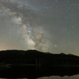 A luminous Milky Way and stars are reflected on the surface of Sprague Lake at Rocky Mountain National Park, Colorado.