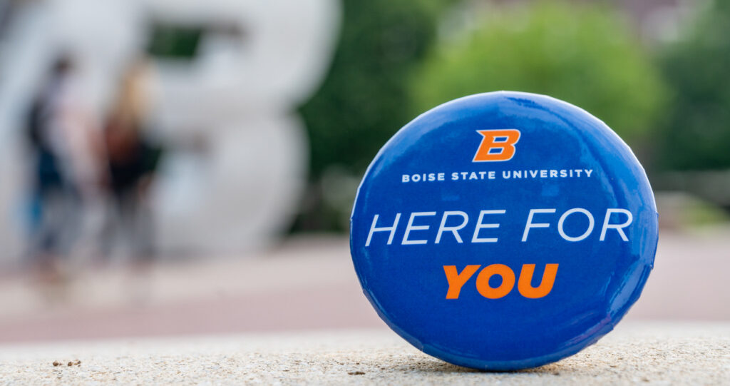 Image of Boise State Univesity branded button with words stating "Here For You"